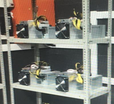 Photo of Bitcoin Antminer mining rigs stacked on metal shelving